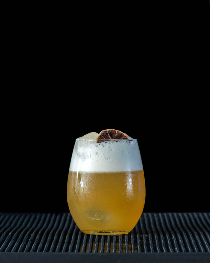 The Amaretto Sour on a bar countertop with a black background