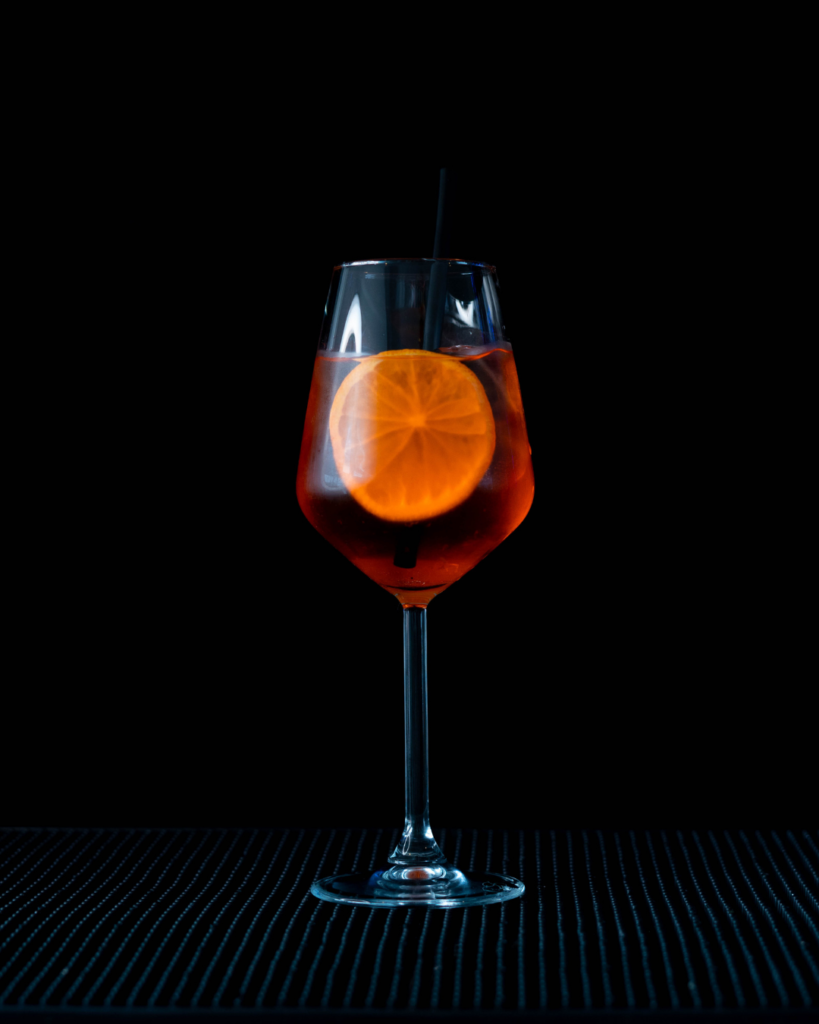 The Aperol Spritz on a bar countertop with a black background