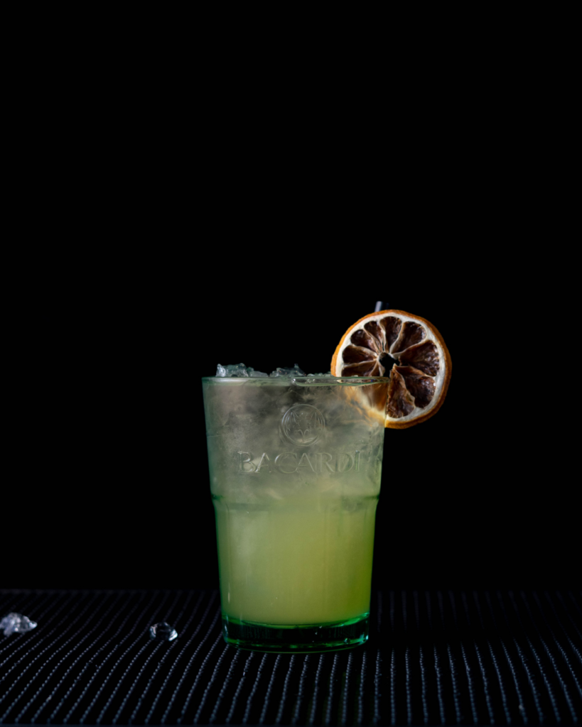 The Coco Colada Spritz on a bar top with a black background