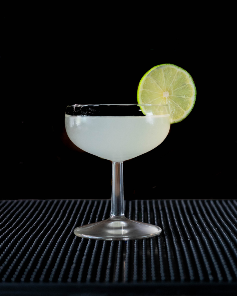 The Daiquiri on a bar countertop with a black background