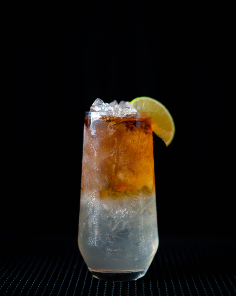 The Dark 'N' Stormy on a bar countertop with a black background