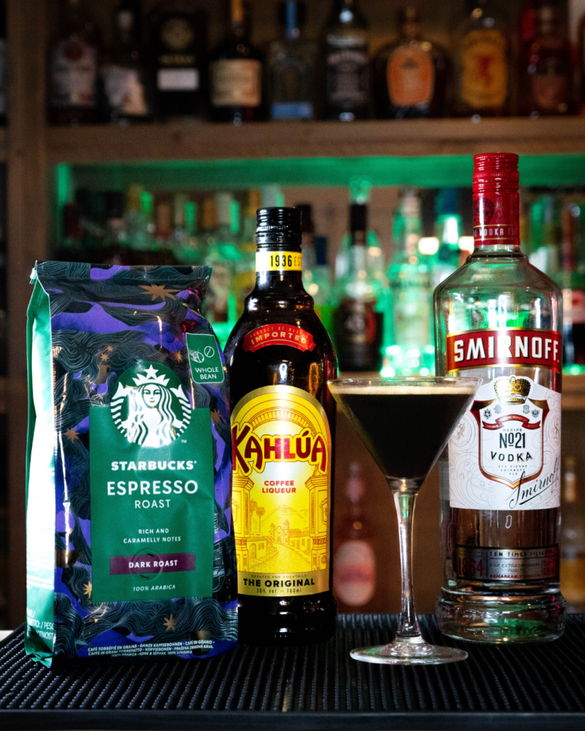 The Espresso Martini on a bar countertop, surrounded by its ingredients