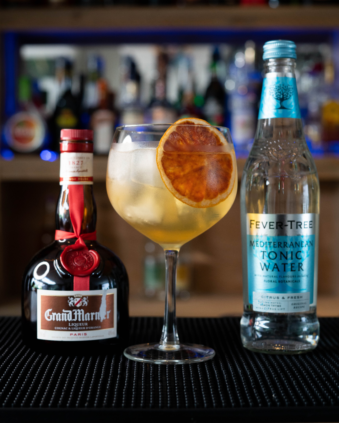 The Grand Tonic on a bar top, surrounded by its ingredients.