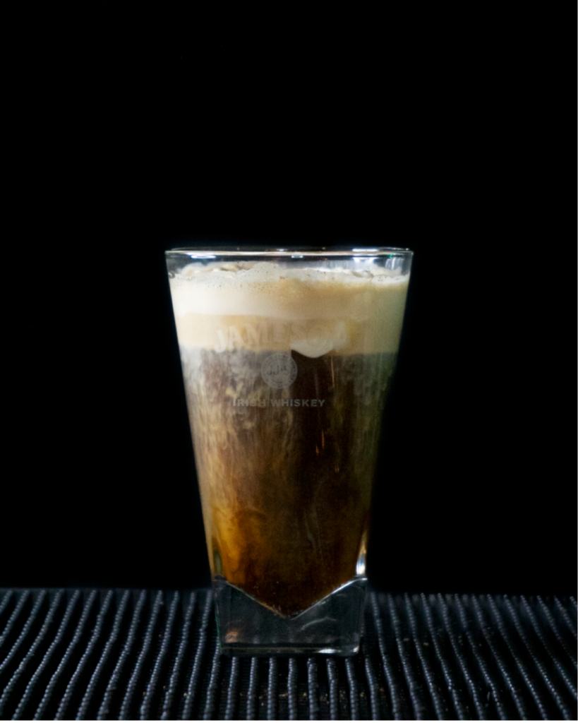 Irish Coffee on a bartop with a black background.