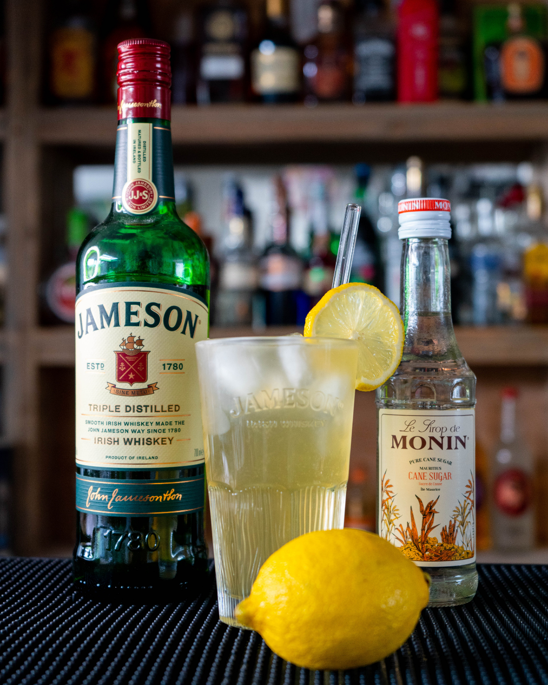 The Irish Lemonade on a bar top, surrounded by its ingredients.