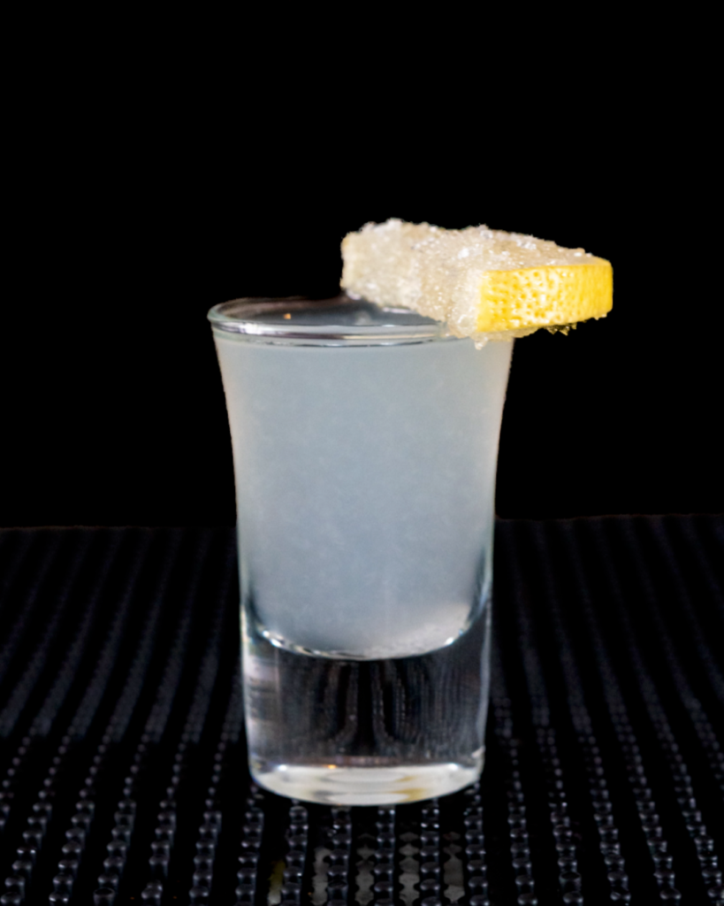 The Lemon Drop Shot on a bar countertop with a black background