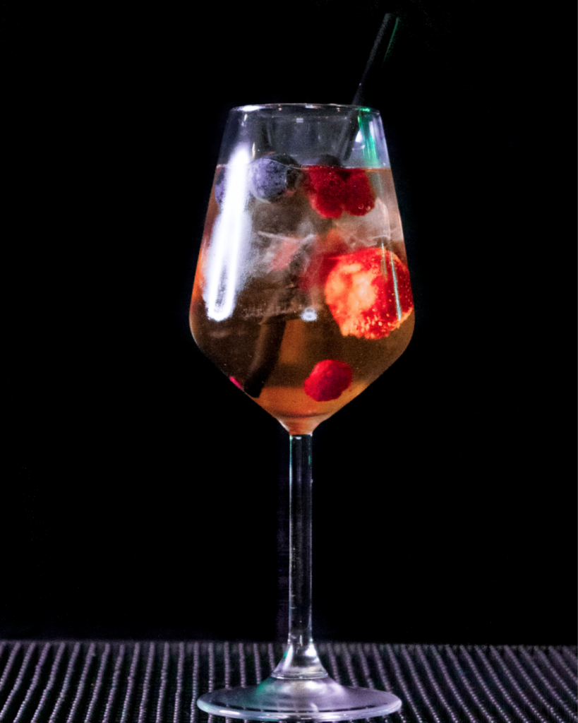 The Wildberry Lillet on a bar top with a black background.