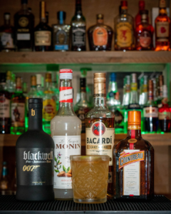 The Mai Tai on a bartop, surrounded by its ingredients