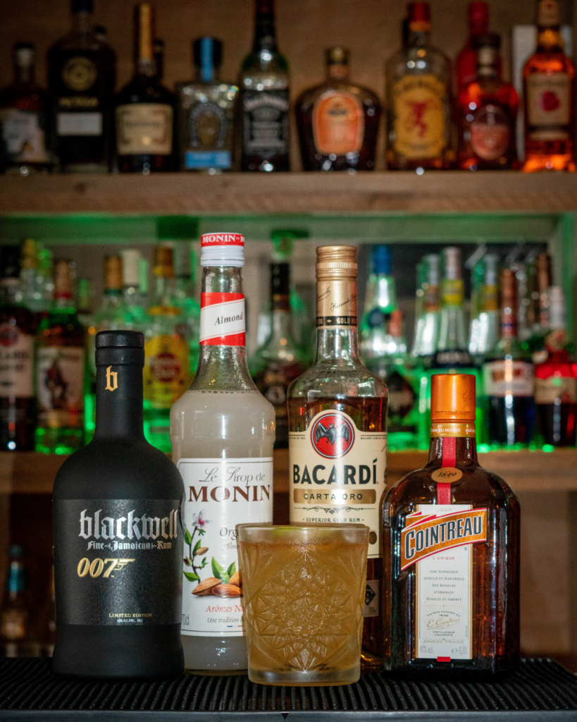 The Mai Tai on a bartop, surrounded by its ingredients