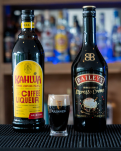 The Baby Guinness Shot on a home bar top, surrounded by its ingredients