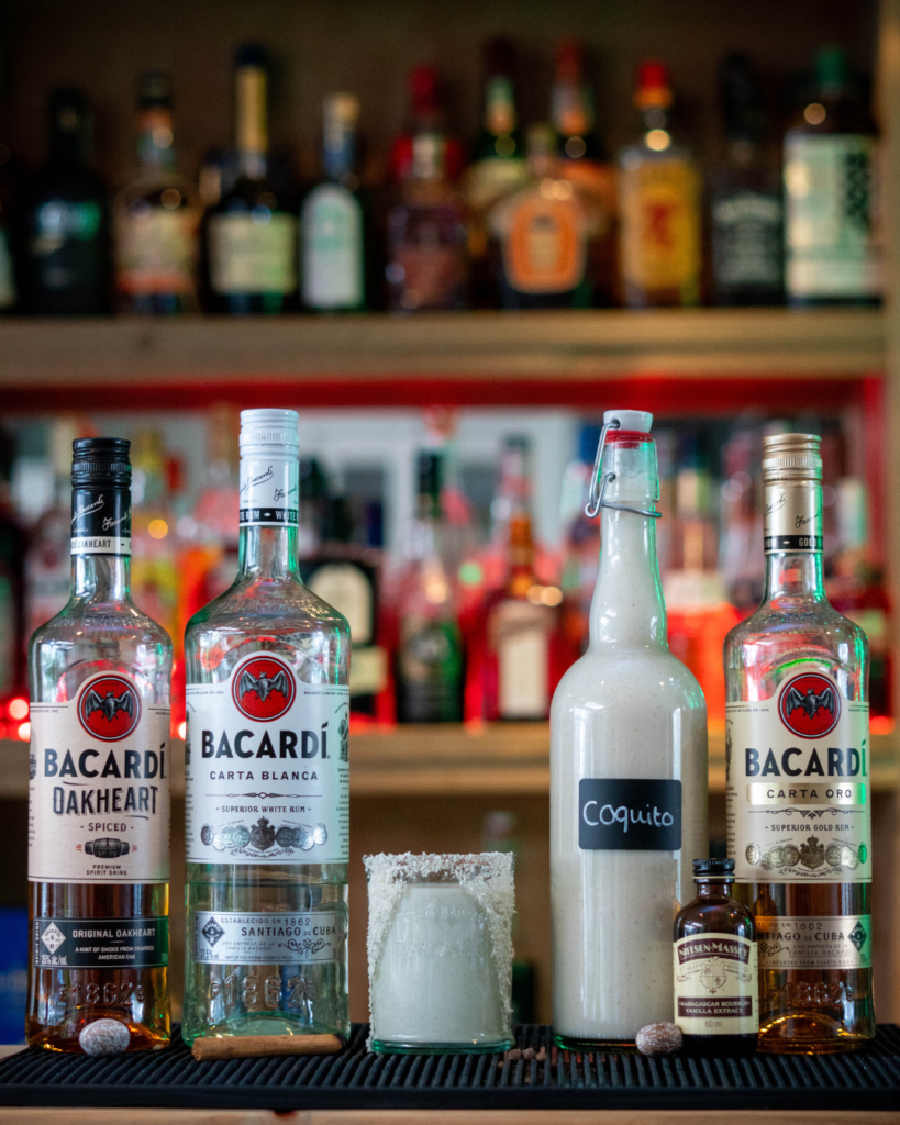 The Coquito on a bartop, surrounded by its ingredients