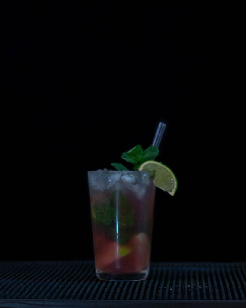 The Cranberry Mojito on a bartop with a black background