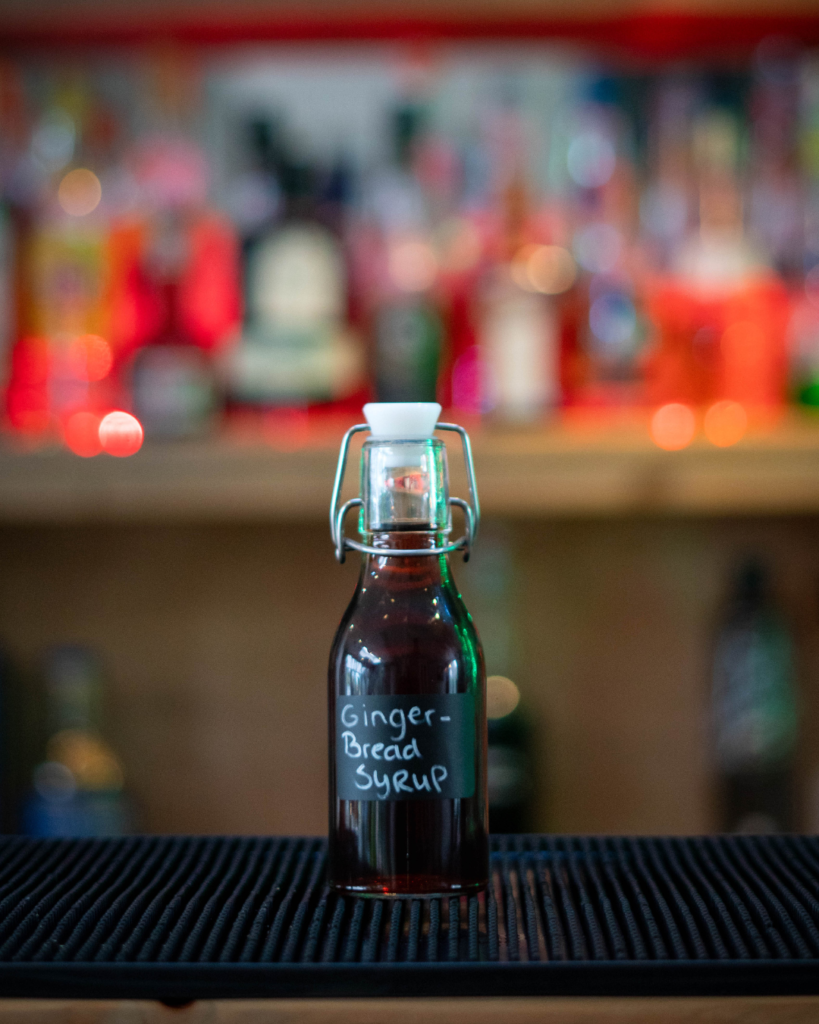 Gingerbread Syrup in a small bottle on a bar top.