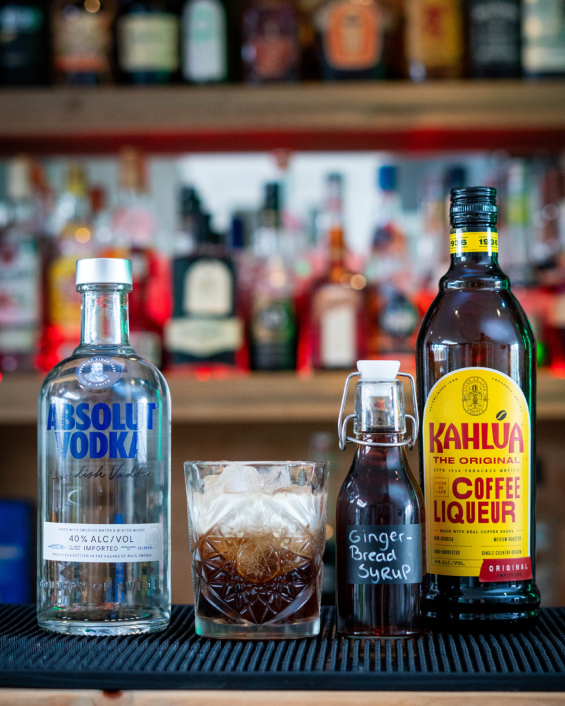 The Gingerbread White Russian on a bartop, surrounded by its ingredients