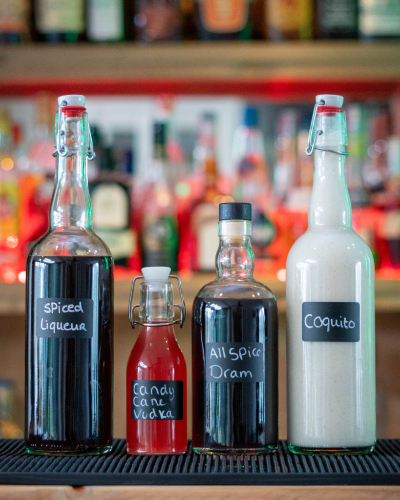 Home made Christmas liqueurs, from left to right: Spiced Liqueur, Candy Cane Vodka, Allspice Dram and Coquito.