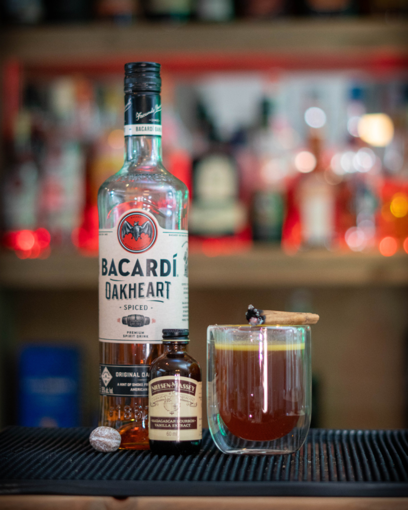 Hot Buttered Rum on a bartop, surrounded by its ingredients