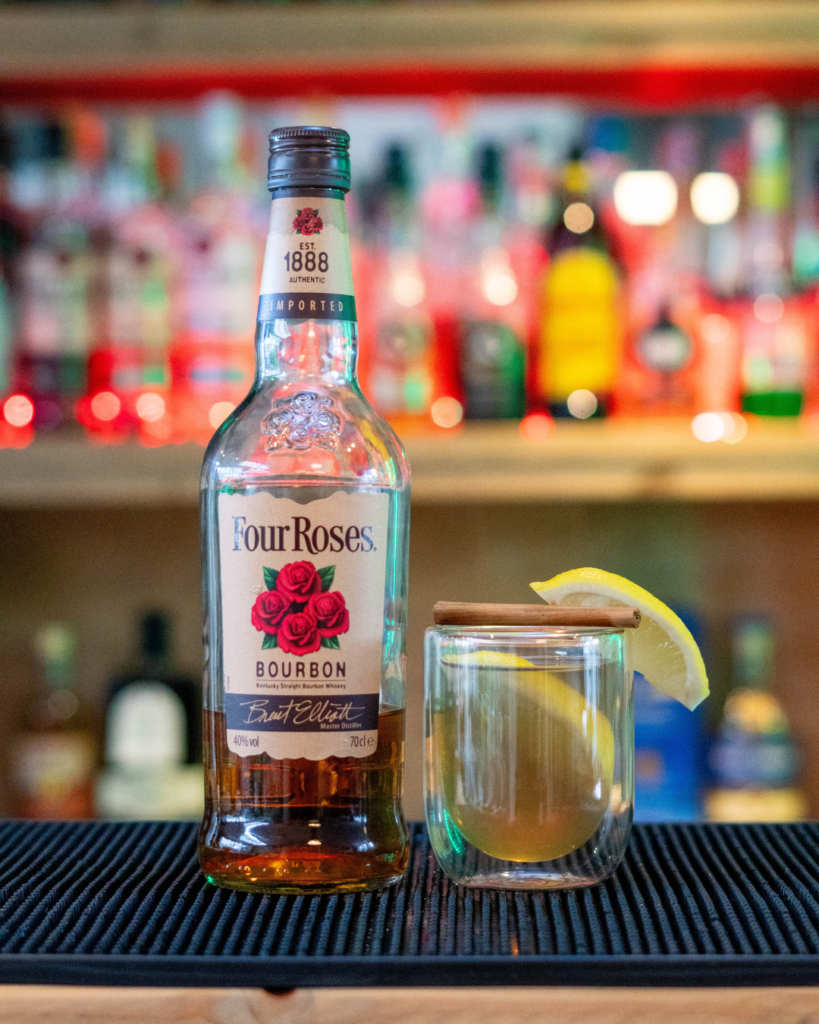 The Hot Toddy on a bar top, surrounded by its ingredients