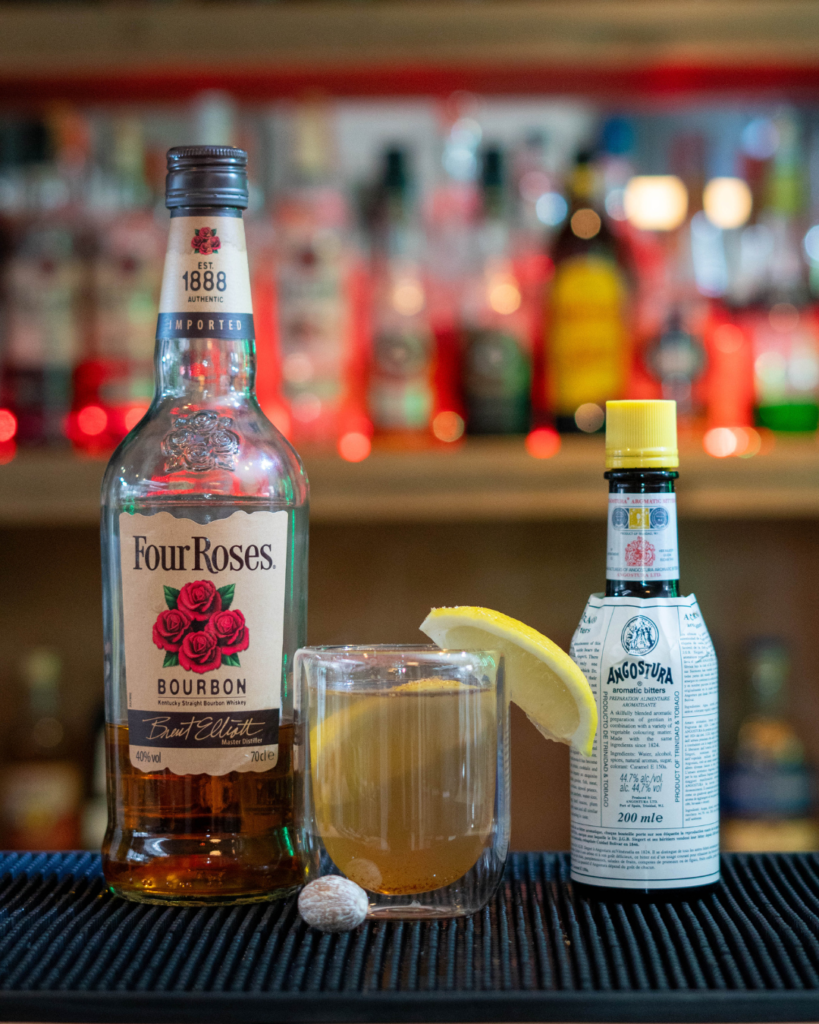 The Nutmeg Hot Toddy on a bartop, surrounded by its ingredients