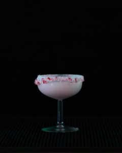 The Candy Cane Martini on a bar top with a black background.
