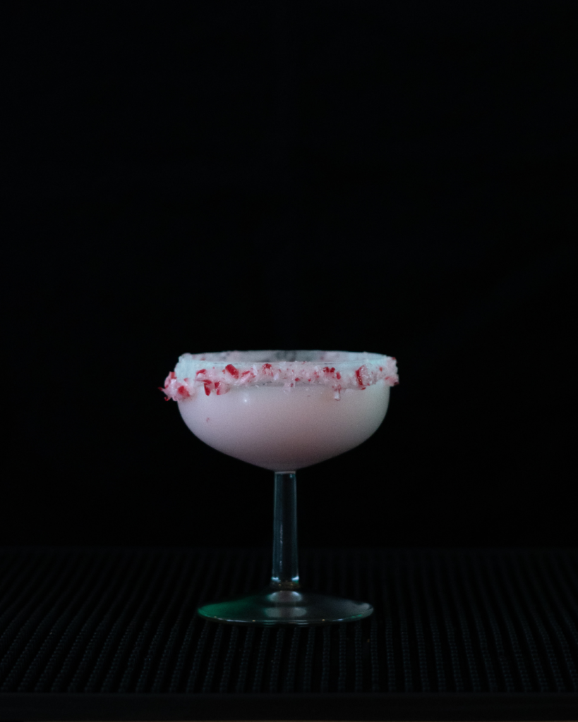 The Candy Cane Martini on a bar top with a black background.