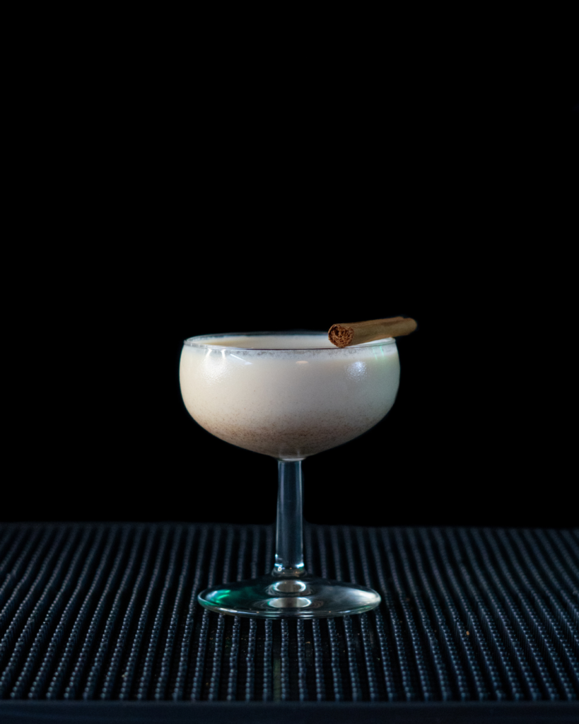 The Eggnog Martini on a bar top wit a black background.