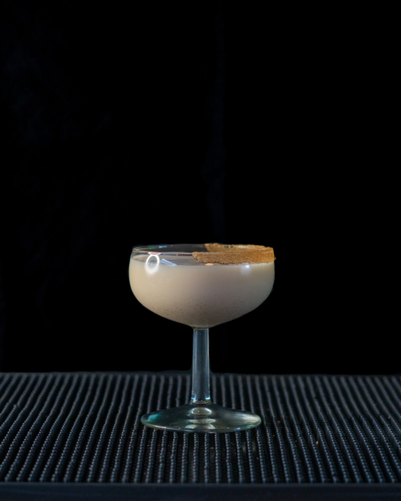 The Spiced Eggnog Martini on a bar top with a black background