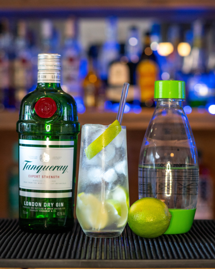 The Gin Rickey on a bartop, surrounded by its ingredients.