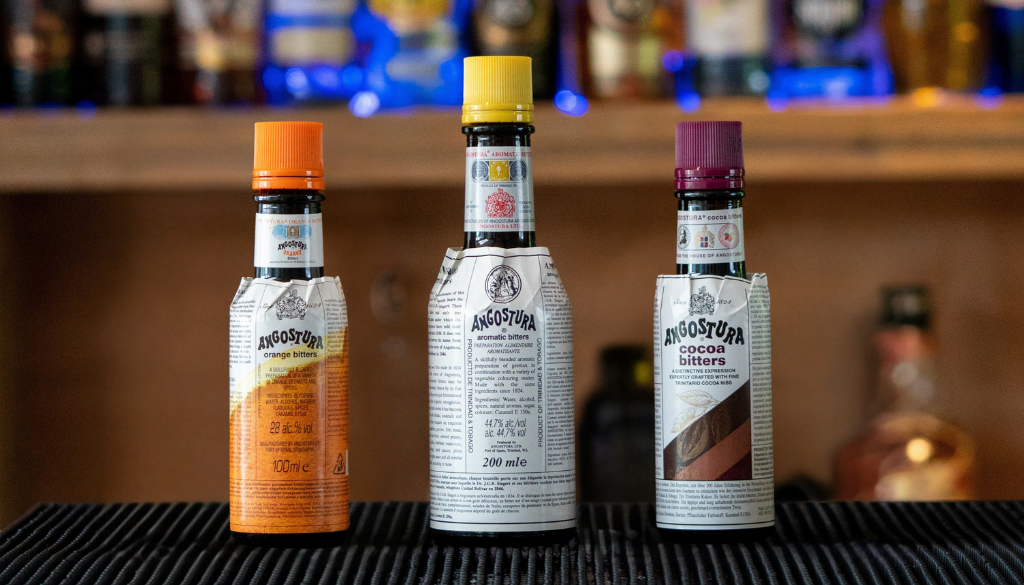 3 bottles of Angostura bitters on a home bartop. Left to right: Angostura Orange Bitters, Angostura Bitters, Angostura Cacao Bitters.