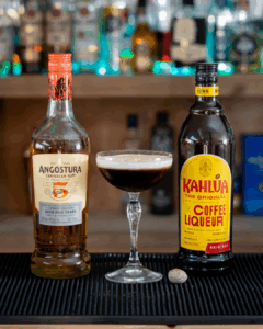 The Dominicana drink on a home bartop, surrounded by its ingredients