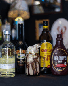 Mudslide Cocktail surrounded by its ingredients on a Home Bar top