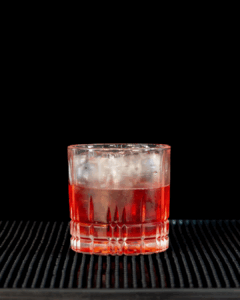 The Negroni Sbagliato on a home bartop with a black background.