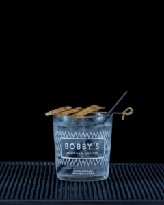 Bobby's Pinang Raci Gin & Fever-Tree Indian Tonic Water mixed on a home bartop with a black background..