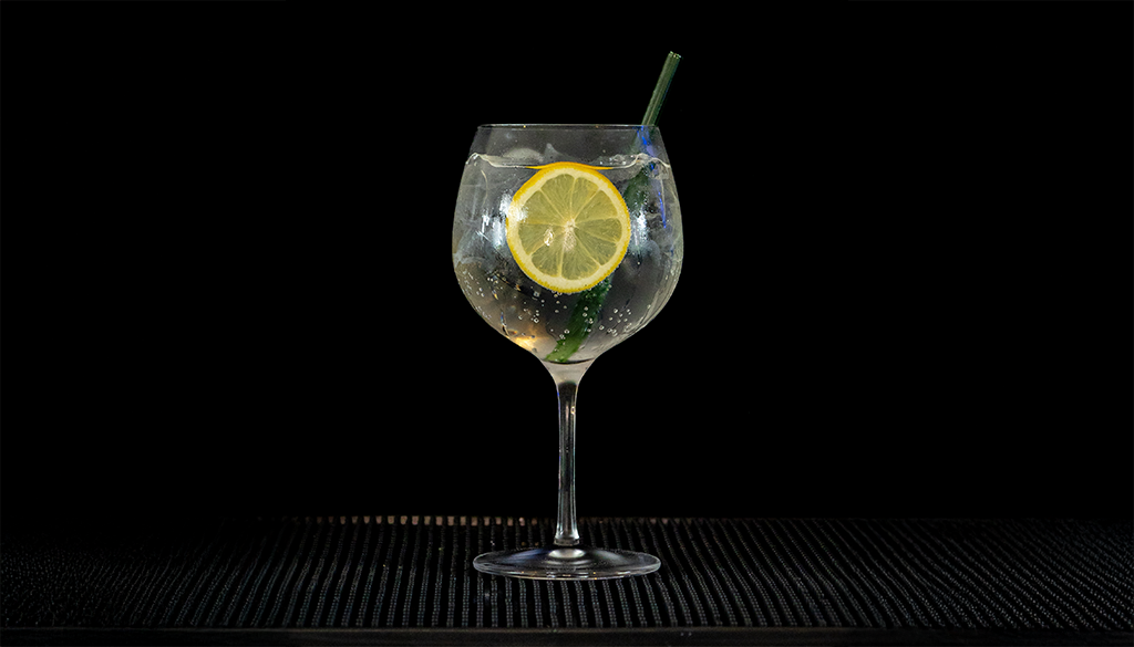 Gin & Tonic: Gordon's London Dry Gin & Schweppes Indian Tonic mixed on a home bartop with a black background..