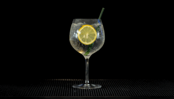 Gin & Tonic: Gordon's London Dry Gin & Schweppes Indian Tonic mixed on a home bartop with a black background..