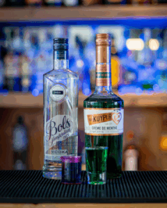 The Boo-zy Lab Kit, Halloween shots; the green shot. The shots on a home bartop, surrounded by its ingredients.