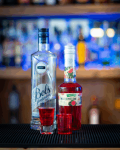 The Boo-zy Lab Kit, Halloween shots; the red shot. The shots on a home bartop, surrounded by its ingredients.