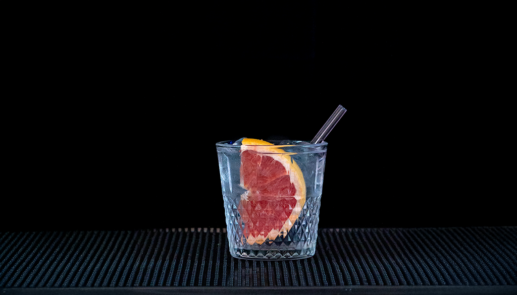 Empress Gin and Fever-Tree Elderflower Tonic mixed in a glass on a home bartop with a black background.