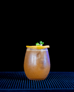 The Jack-'o'-Lantern Halloween Cocktail on a home bartop with a black background.