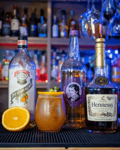 The Jack-'o'-Lantern Halloween Cocktail on a home bartop surrounded with its ingredients.