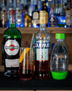 the Americano cocktail on a home bartop surrounded by its ingredients.