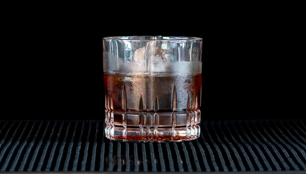 The Black Russian on a home bartop, with a black background.