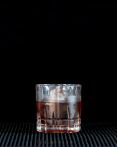 The Black Russian on a home bartop, with a black background.