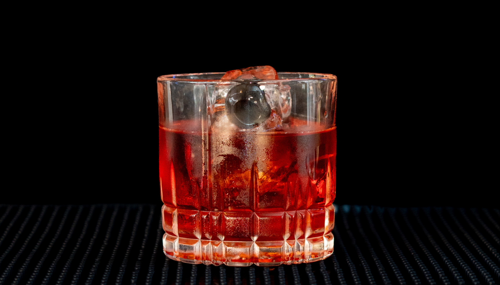the Boulevardier cocktail on a home bartop with a back background.