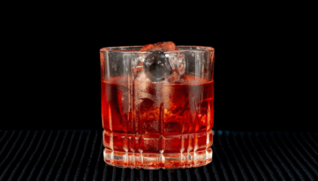 the Boulevardier cocktail on a home bartop with a back background.