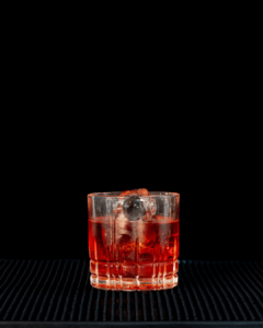 the Boulevardier cocktail on a home bartop with a back background.