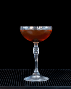 the Manhattan cocktail on a home bartop with a black background.