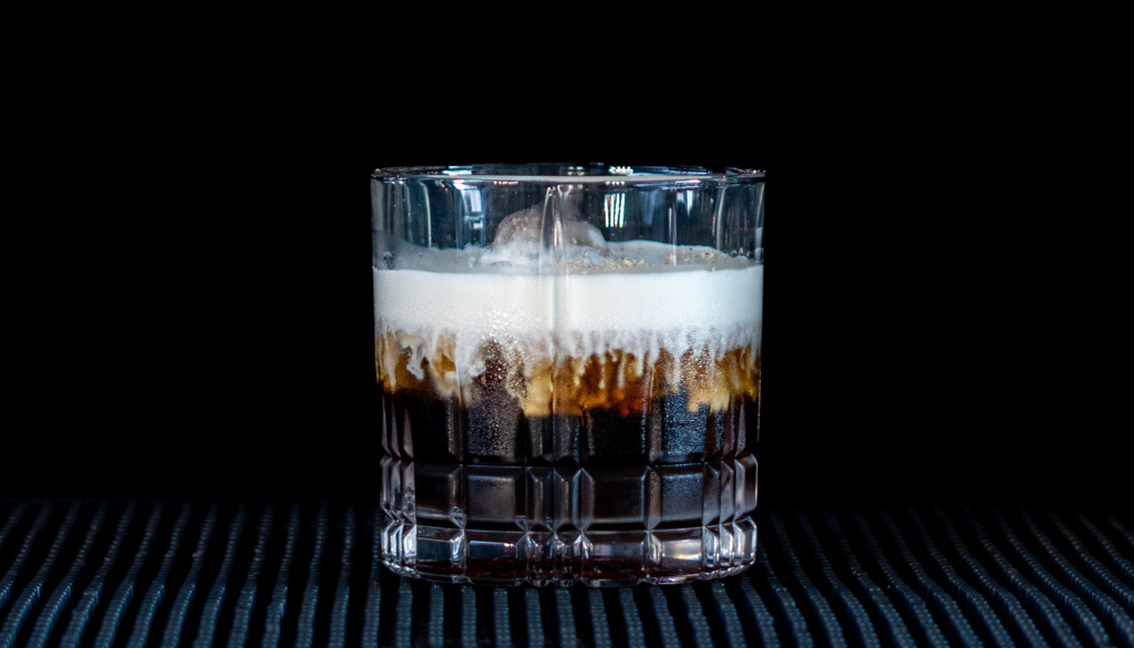 The White Russian on a home bartop, with a black background.
