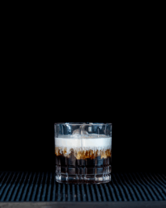 The White Russian on a home bartop, with a black background.