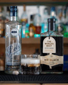 The White Russian on a home bartop, surrounded by its ingredients.