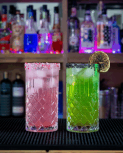 The Green Wicked Cocktail: The Elphaba Cocktail and The Pink Wicked Cocktail: The Glinda Cocktail on a home bartop.